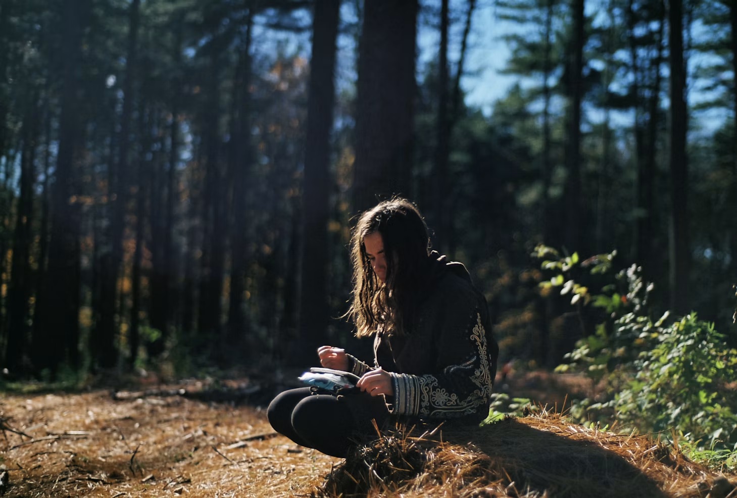A student writing while seated in a forest